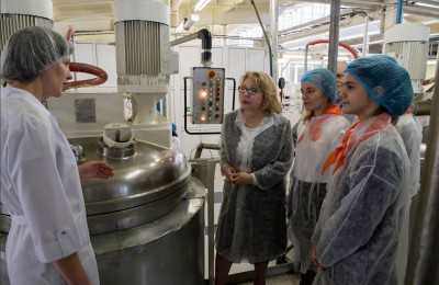 Главный технолог производства рассказывает Елене Паниной и школьникам процесс приготовления косметического крема